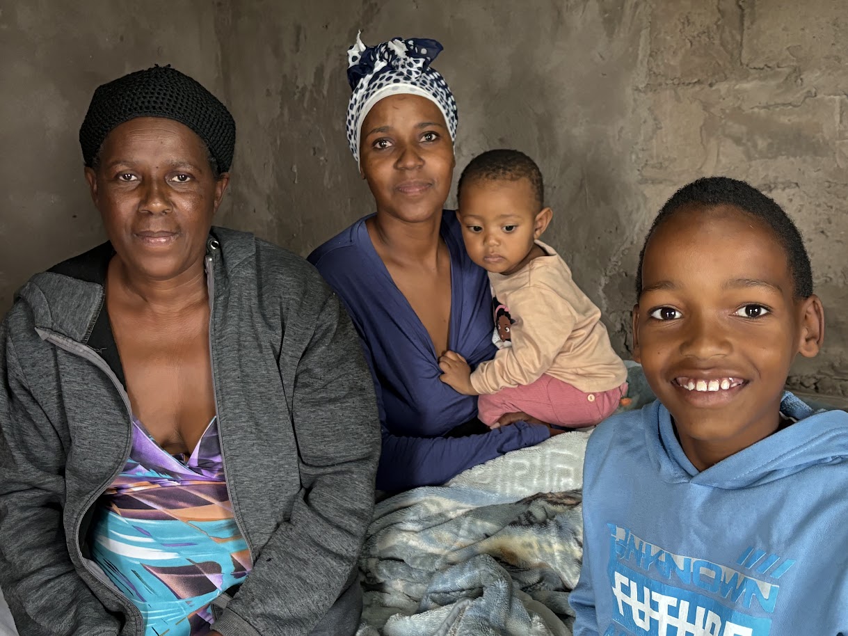 A gogo, mother, baby and older brother inside a Ntshongweni home