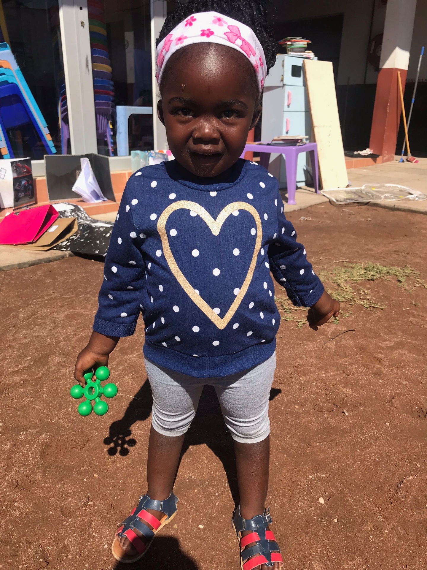 A small girl in a heart sweatshirt standing in the crèche yard