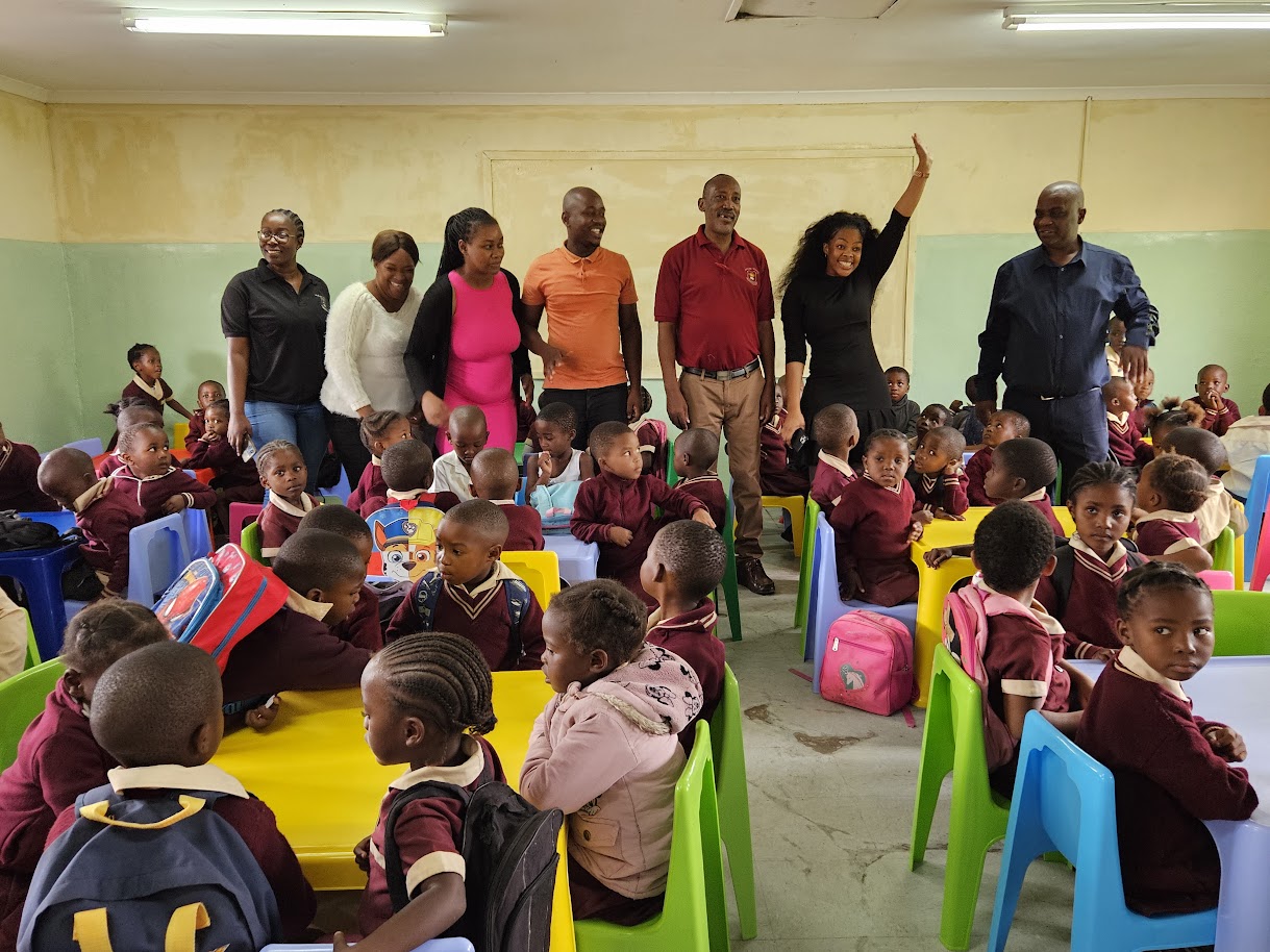 Crèche teachers and staff in a full classroom of children in maroon uniforms