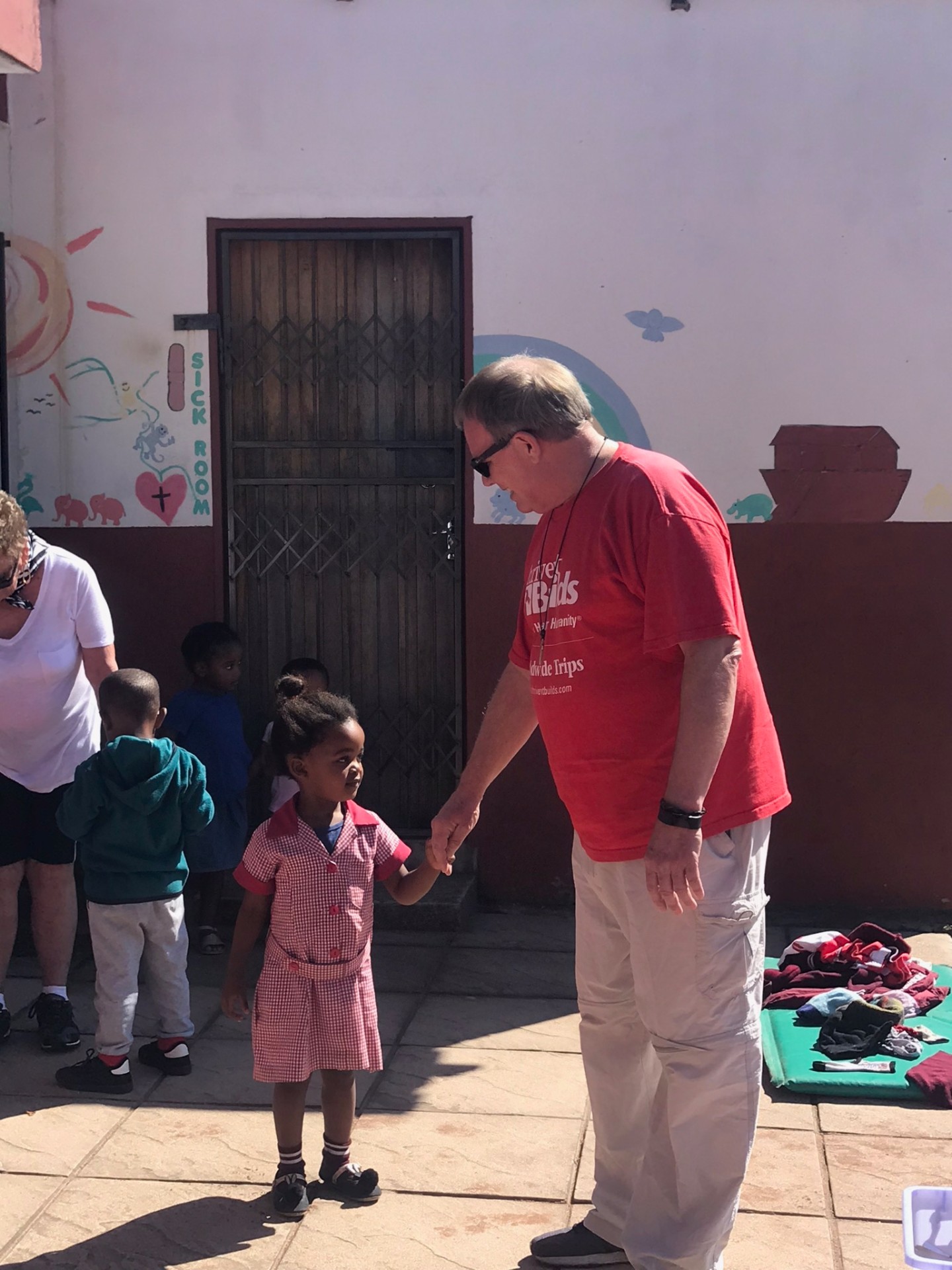 A friend holding the hand of a little girl outside the crèche