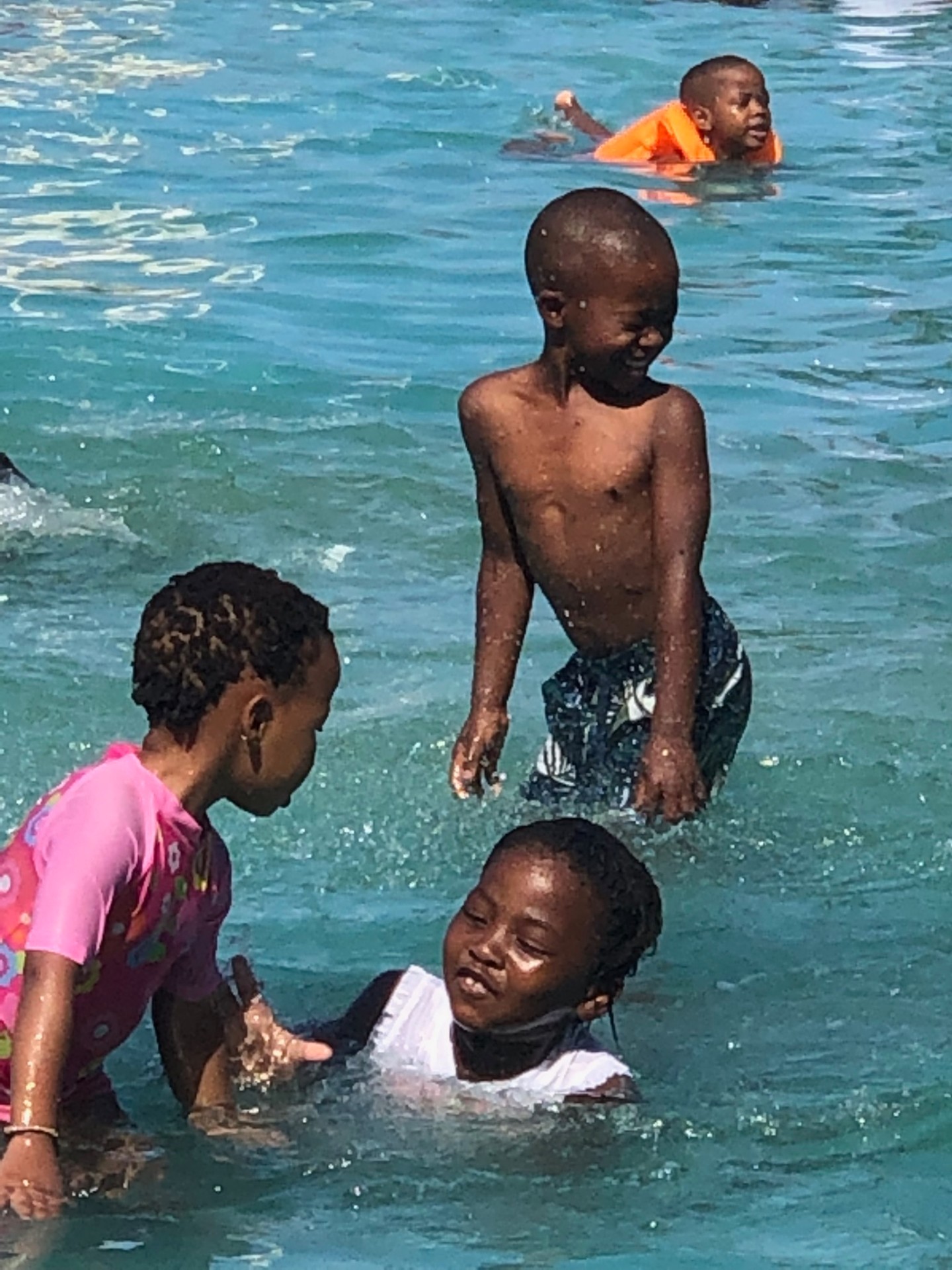 Three children splashing and laughing together in the pool