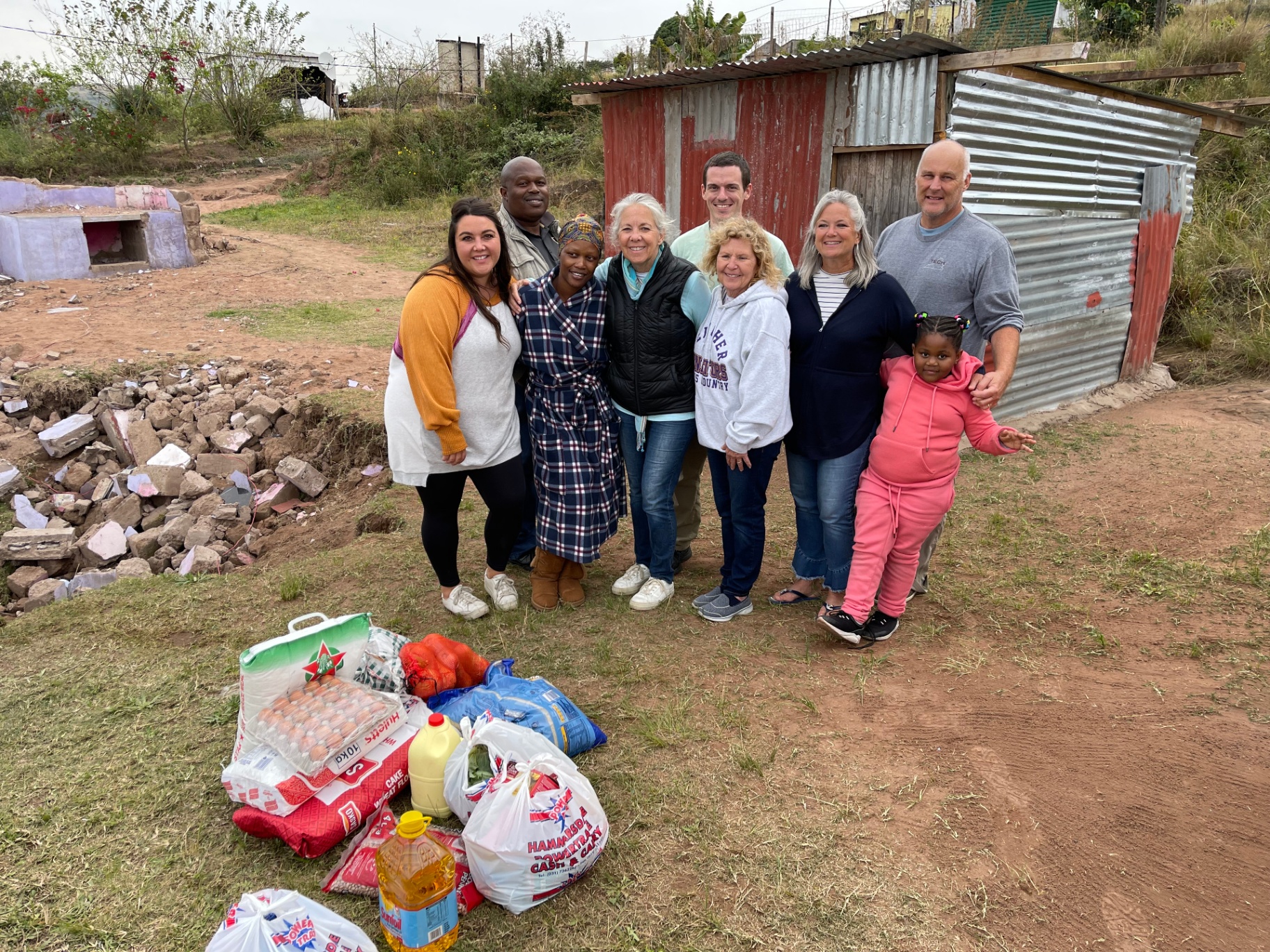 Zanele with the mission crew and food parcels beside the ruins