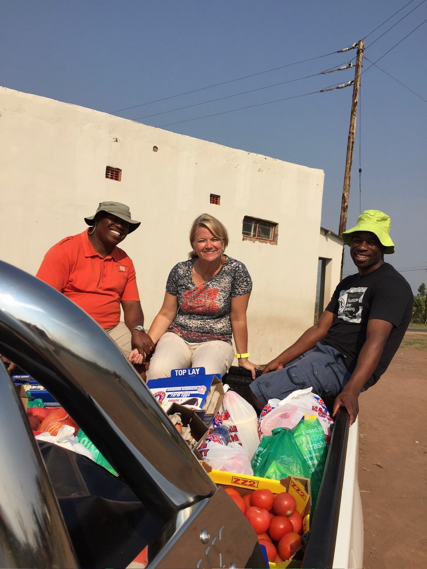 Friends sitting on a pickup truck loaded with food supplies