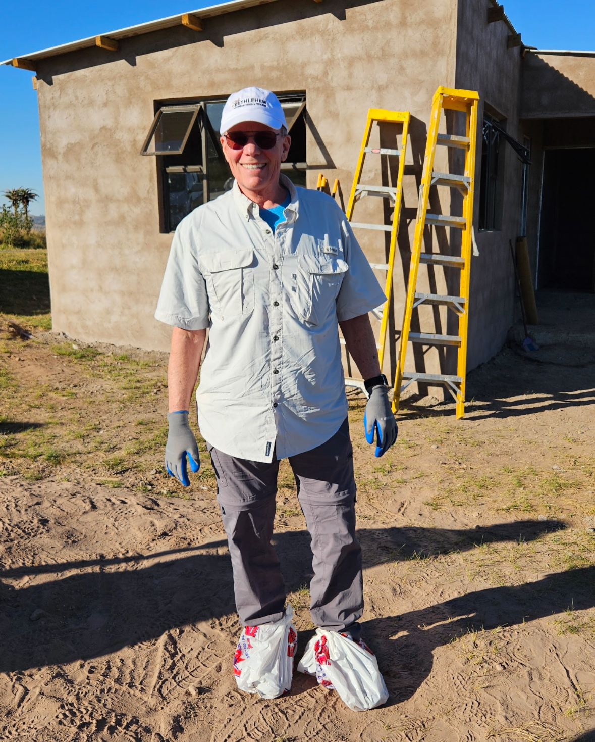 A volunteer smiling in front of the nearly finished new home