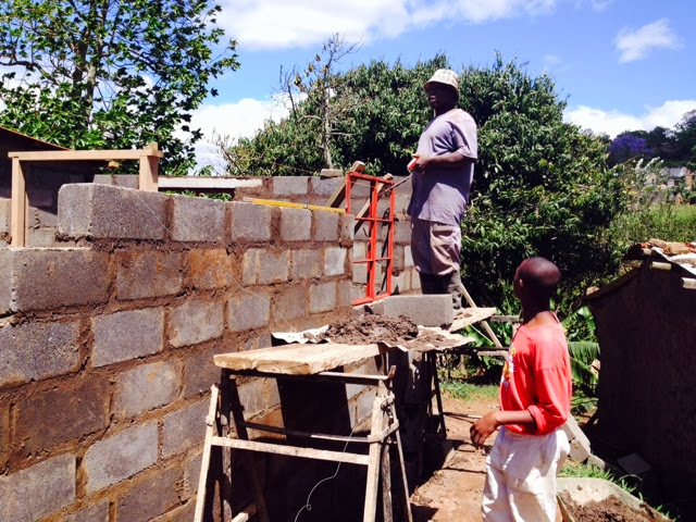 Bricklayer at work on a home build with a young helper