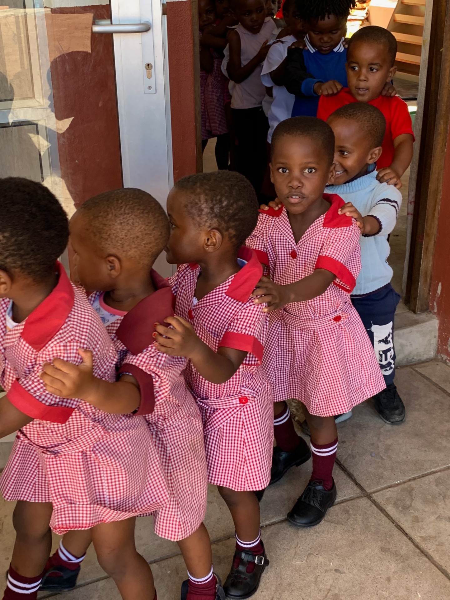 Small crèche girls lining up hand-on-shoulder