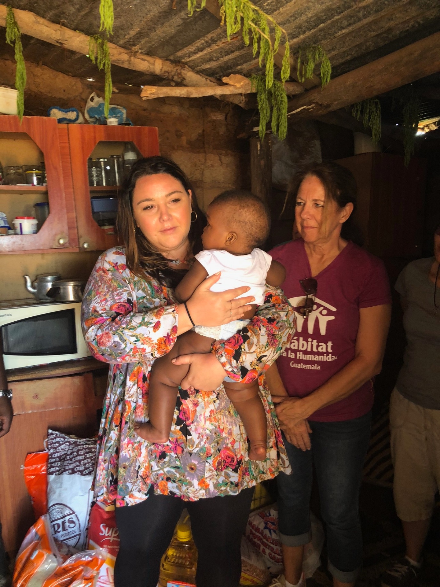 Two friends cradling a Ntshongweni baby together during a family visit