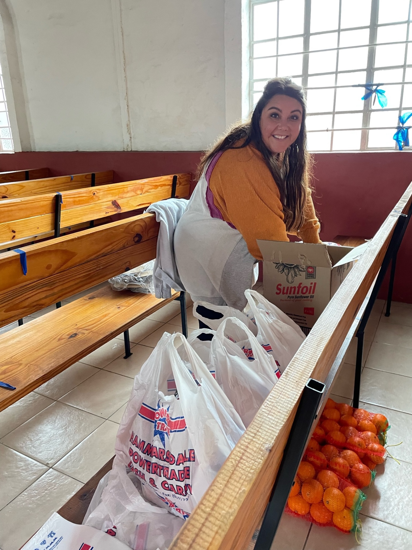A friend of the mission packing individual food parcels in the church before distribution