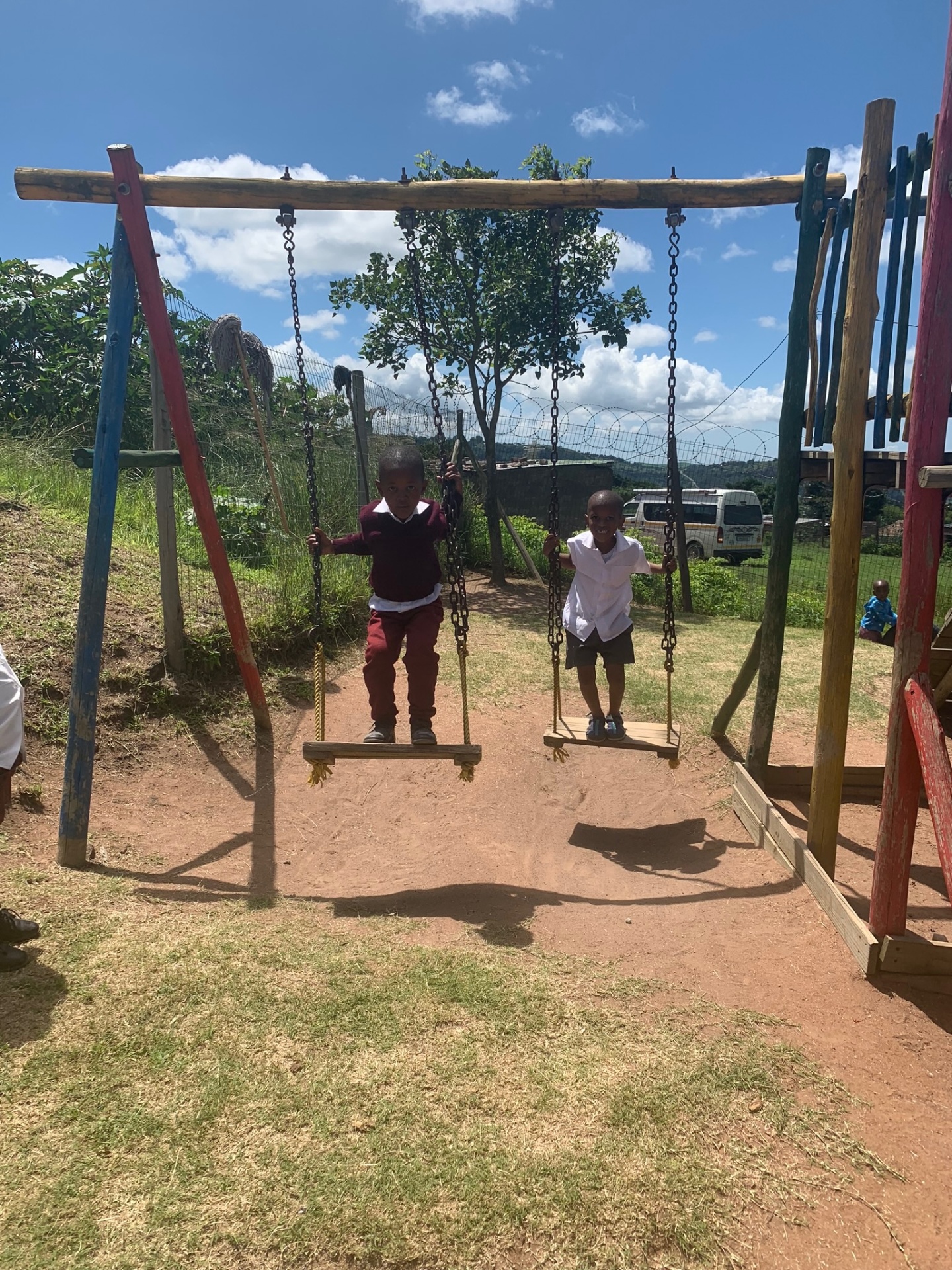Two children smiling on playground swings