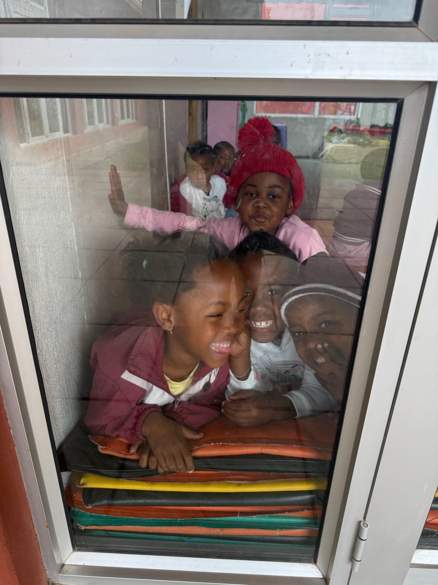 Crèche children laughing against a classroom window