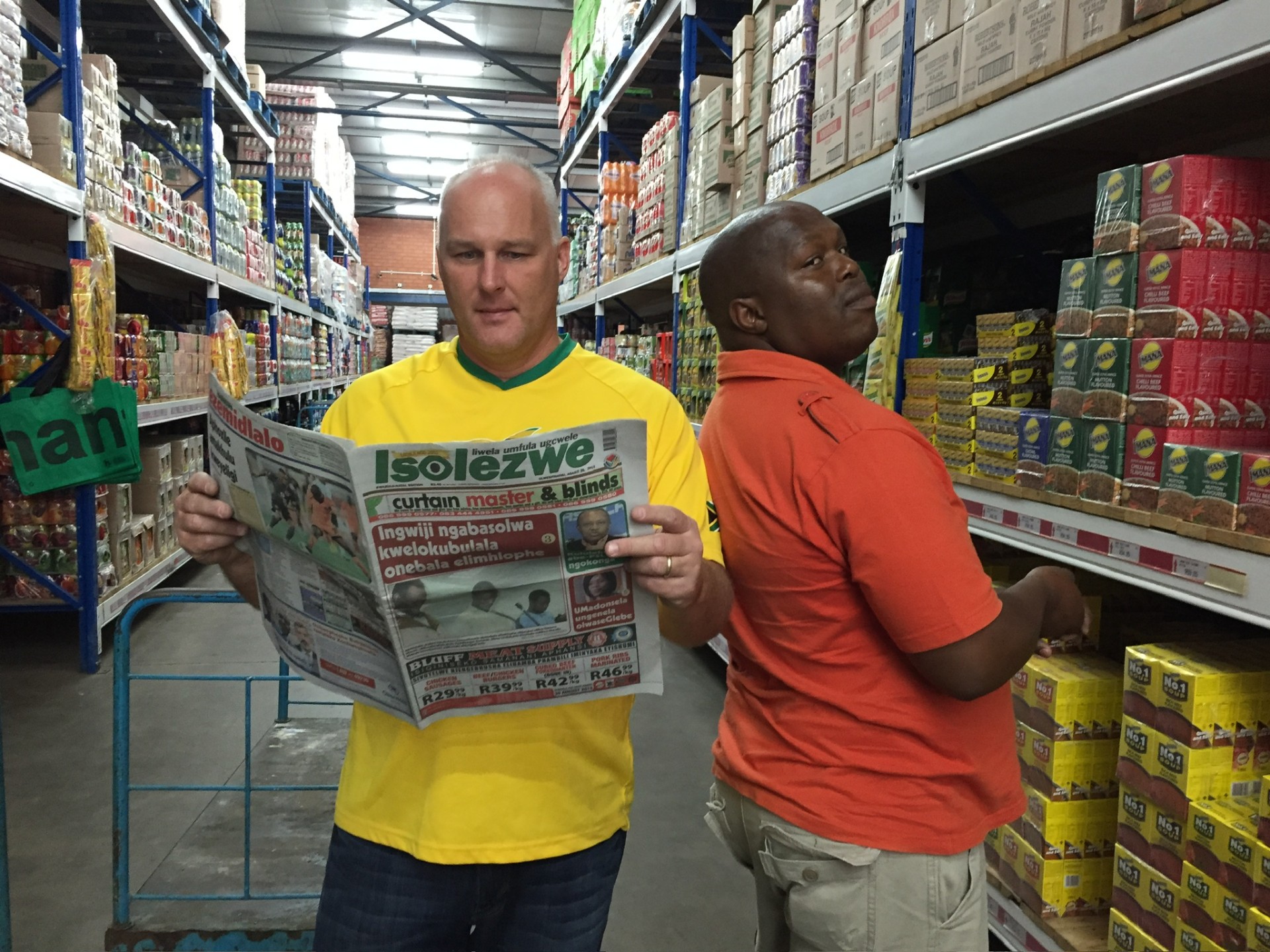 Two long-time mission friends joking together in the wholesale aisle while shopping for bulk food-parcel supplies