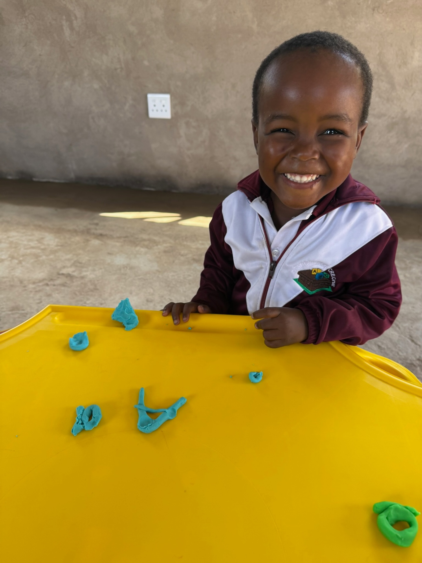 A crèche boy shaping play-dough letters