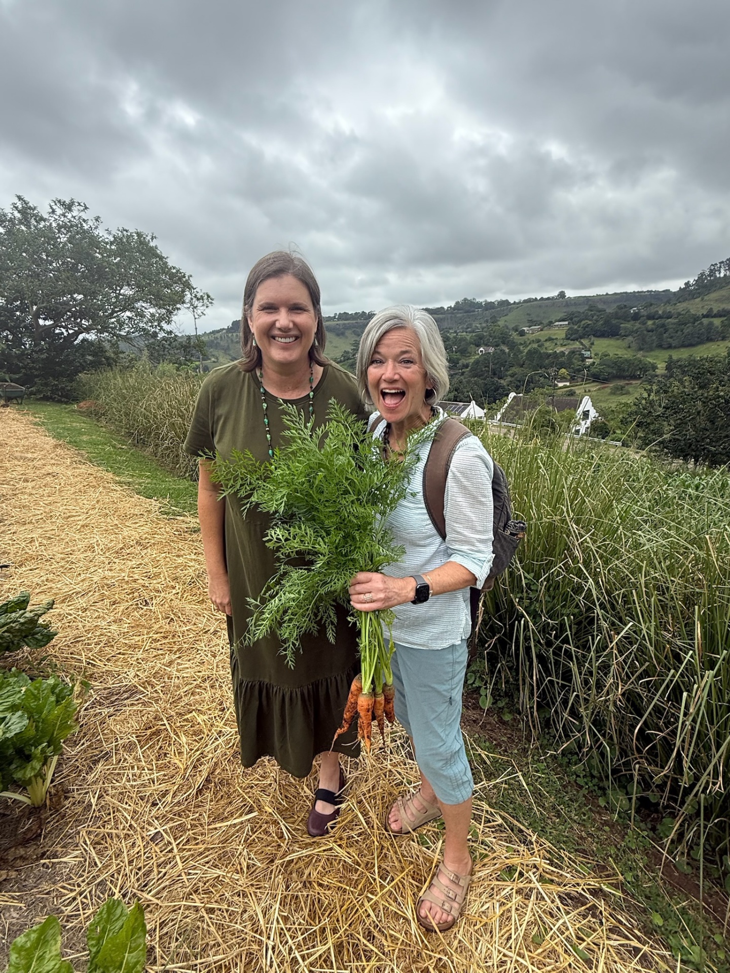 Two mission friends holding a fresh carrot harvest