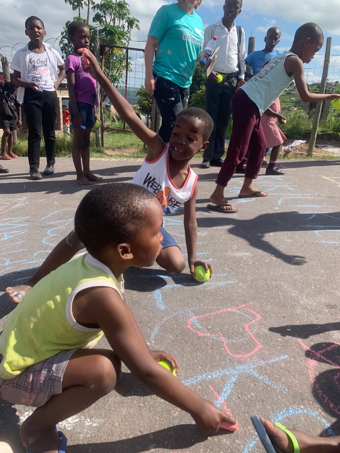 Children crouched over sidewalk chalk drawings
