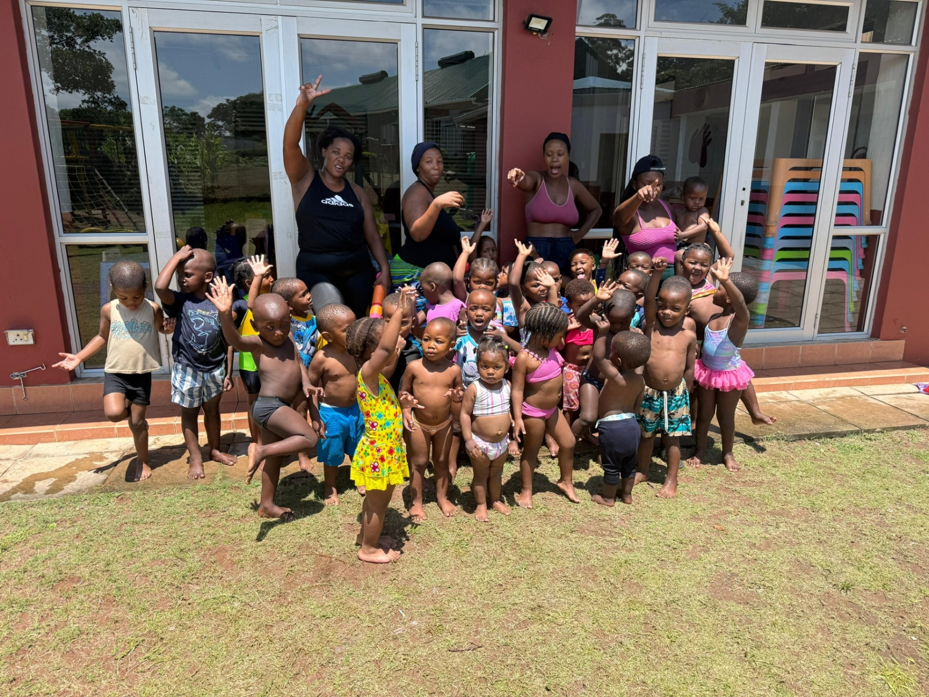 A large group of crèche children and teachers waving