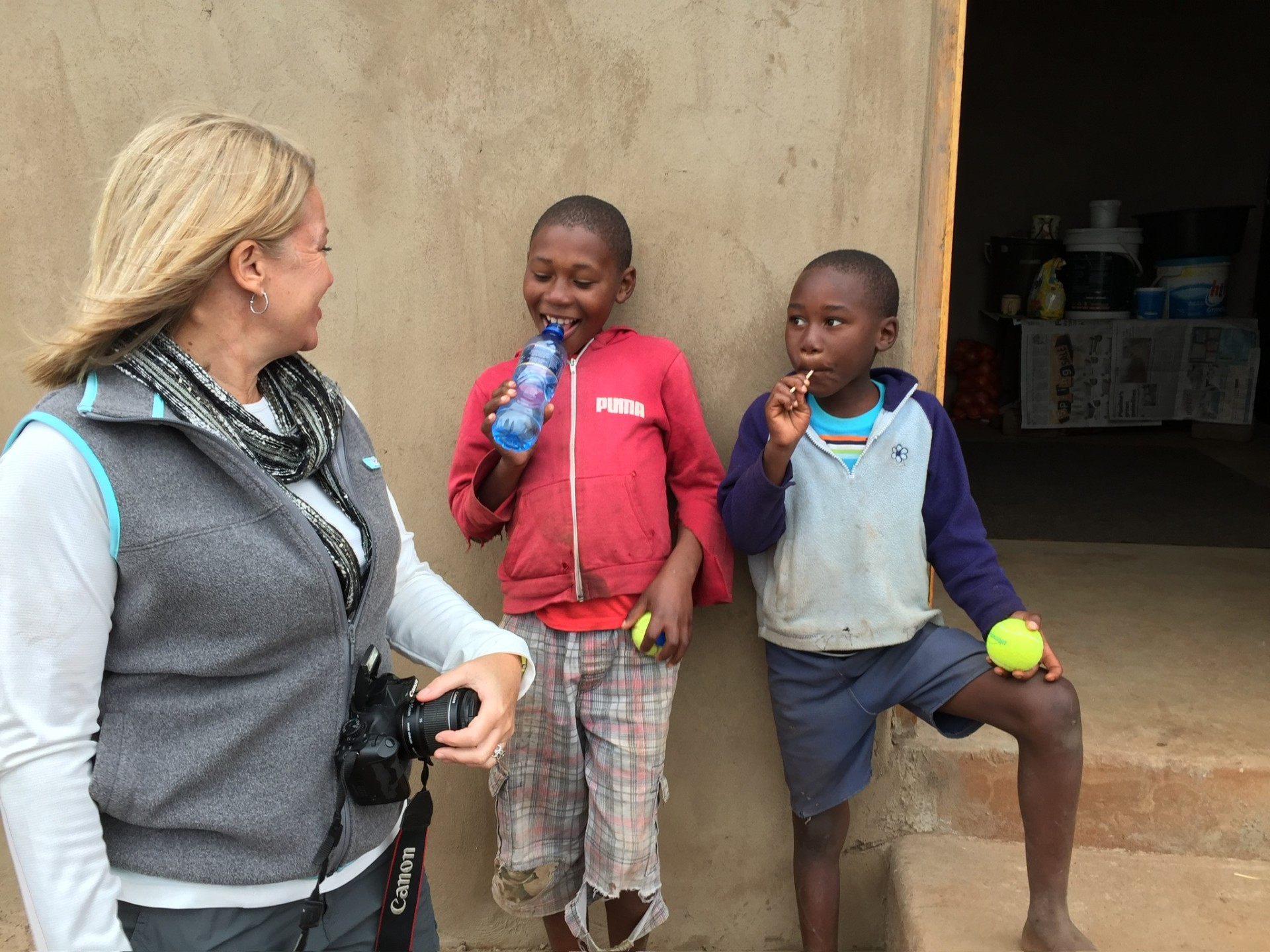 A friend laughing with two boys holding tennis balls