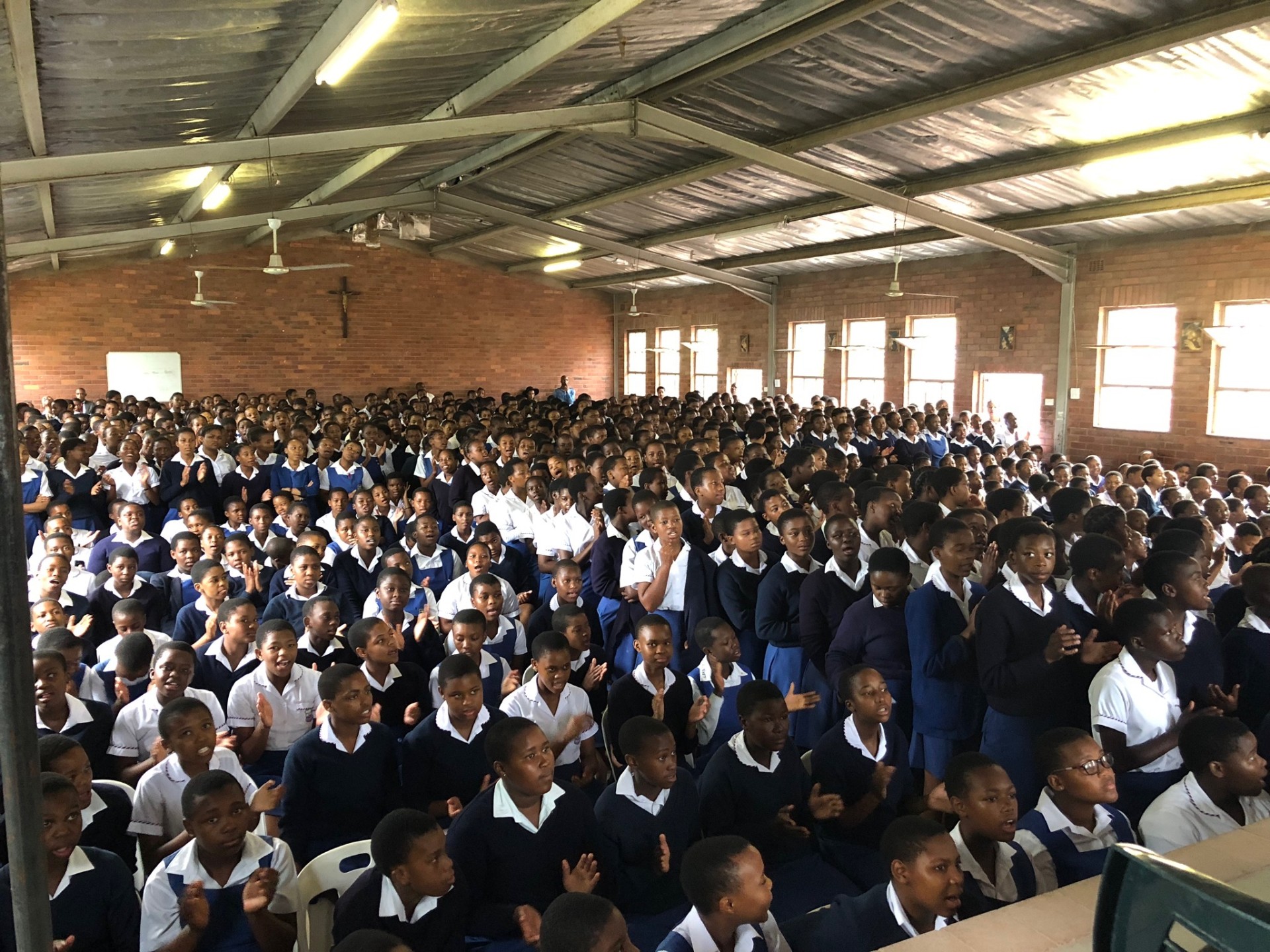 High school students singing in a packed assembly hall