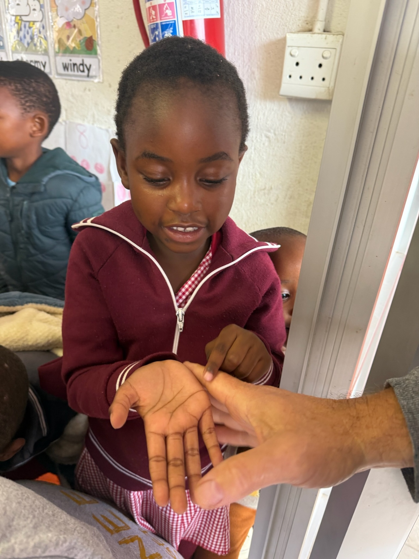 A young girl counting on her fingers with a friend's help