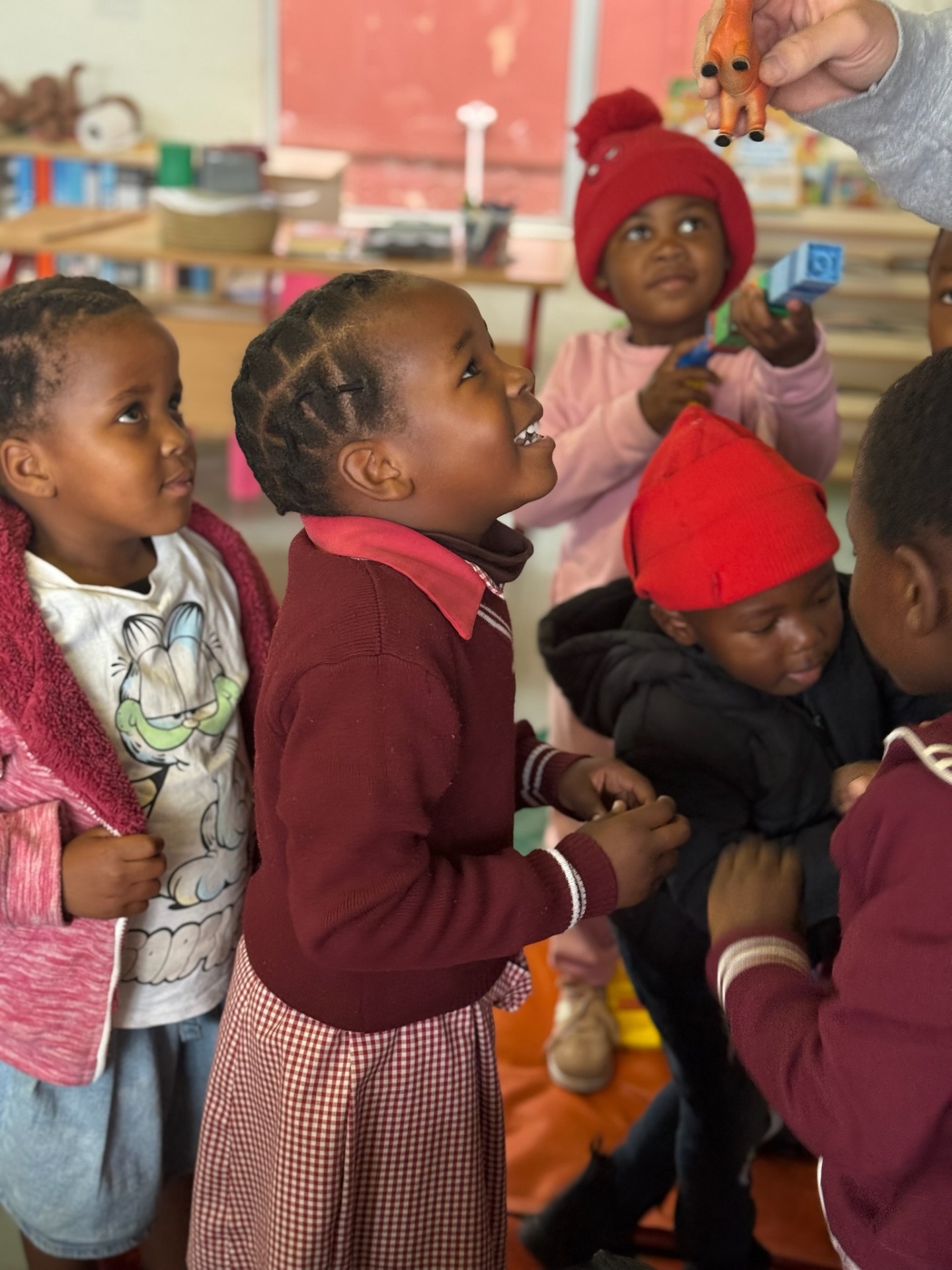 A crèche girl laughing at a small toy