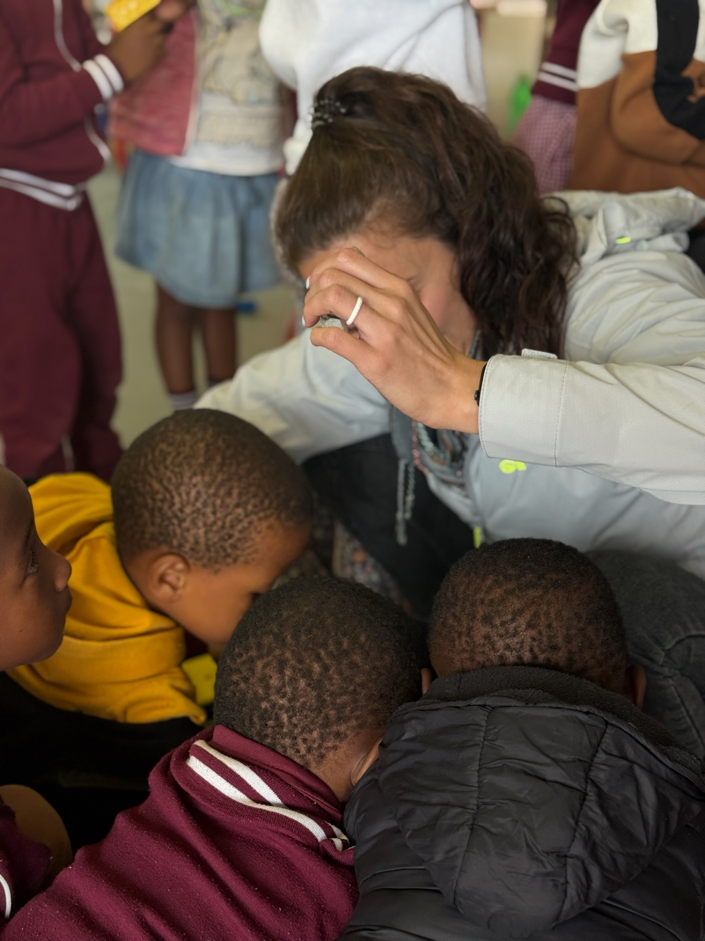A visitor praying over three young children at the crèche