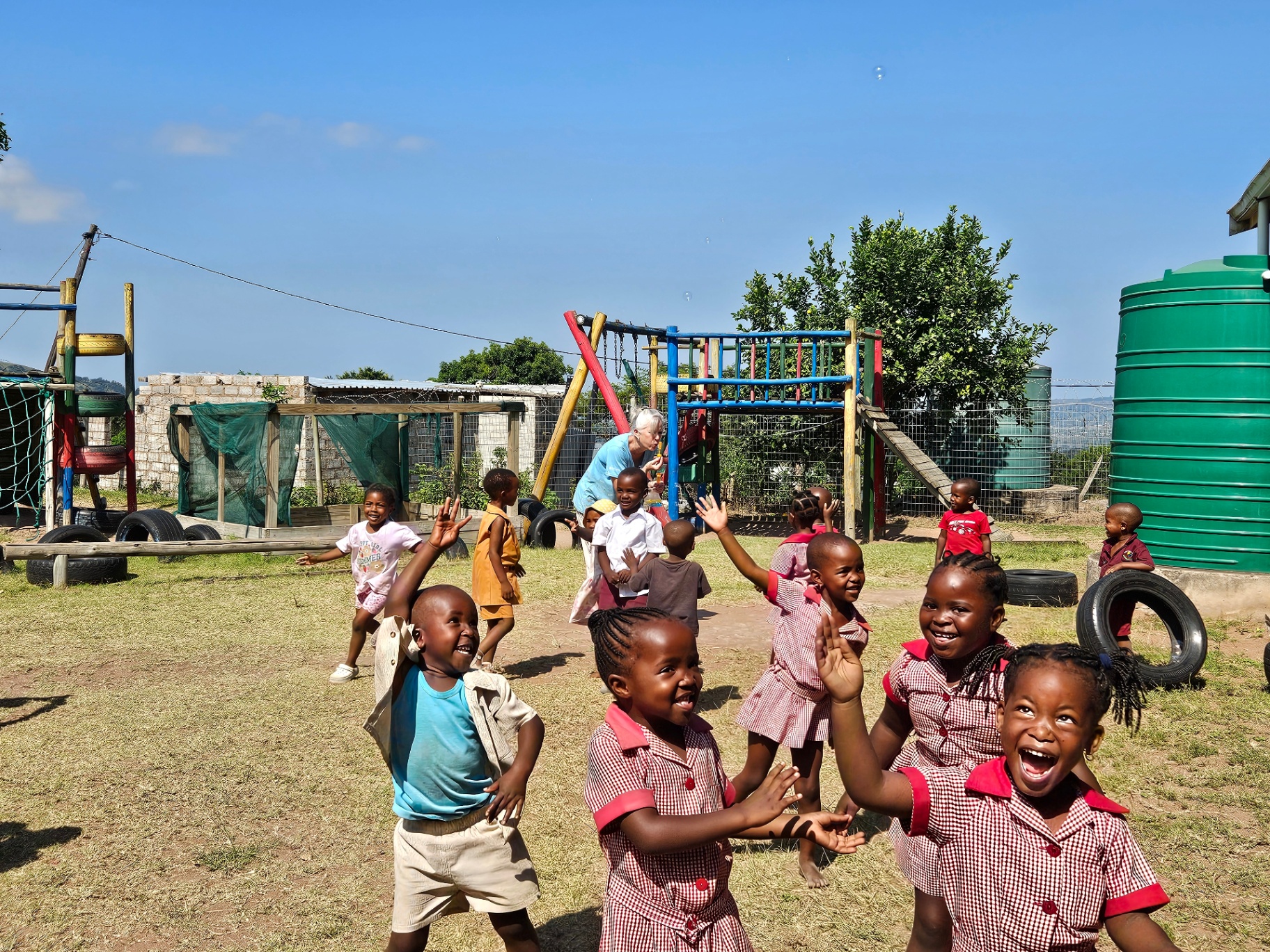 Crèche children laughing and waving in the courtyard