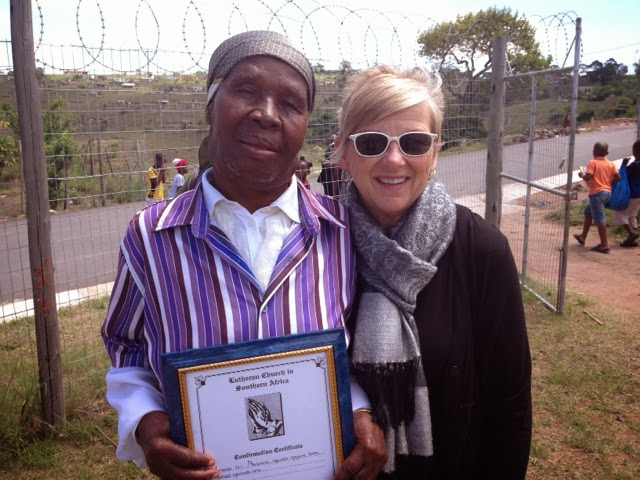 A pastor holding a confirmation certificate with a friend of the mission