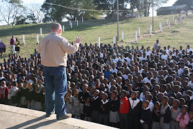 A friend of the mission speaking to hundreds of schoolchildren gathered on a Ntshongweni hillside