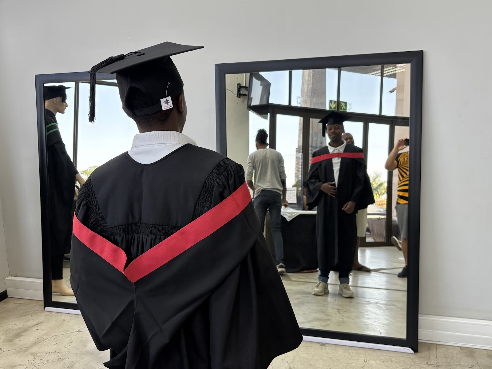Mlondi, Pastor Thwala, and Tshepo with their graduation gowns, the Indian Ocean behind them